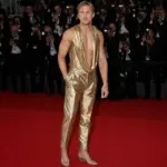 Anonimowy aktor na czerwonym dywanie w złotej stylizacji i przezroczystych butach
