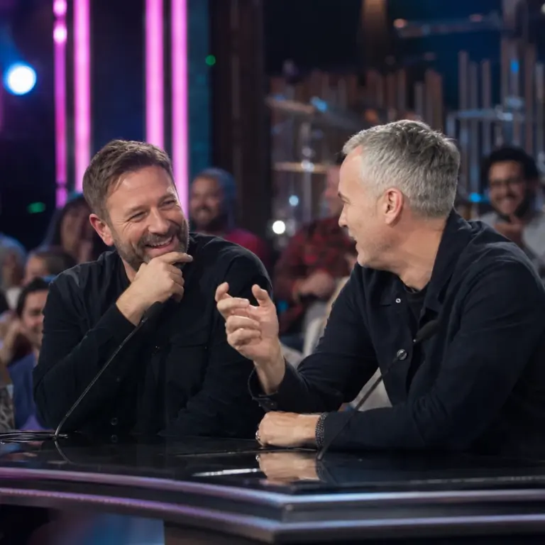 Dwóch anonimowych aktorów prowadzących żartobliwą rozmowę w telewizyjnym studiu muzycznego show o początkach kariery i wyglądzie