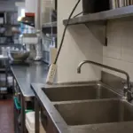 Niezabezpieczony przedłużacz nad zlewem w odnowionej restauracyjnej kuchni