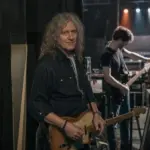 Fotorealistyczna scena inspirowana biograficznym filmem dokumentalnym o powstaniu polskiego zespołu rockowego i karierze gitarzysty