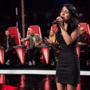 Anonimowa wokalistka podczas występu w telewizyjnym talent show, wybierająca jednego z trenerów po entuzjastycznej reakcji jury